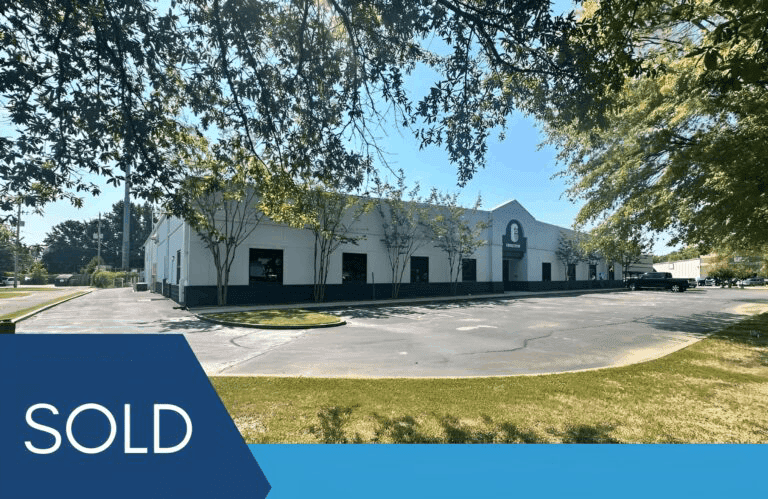 Sold white industrial building with parking lot