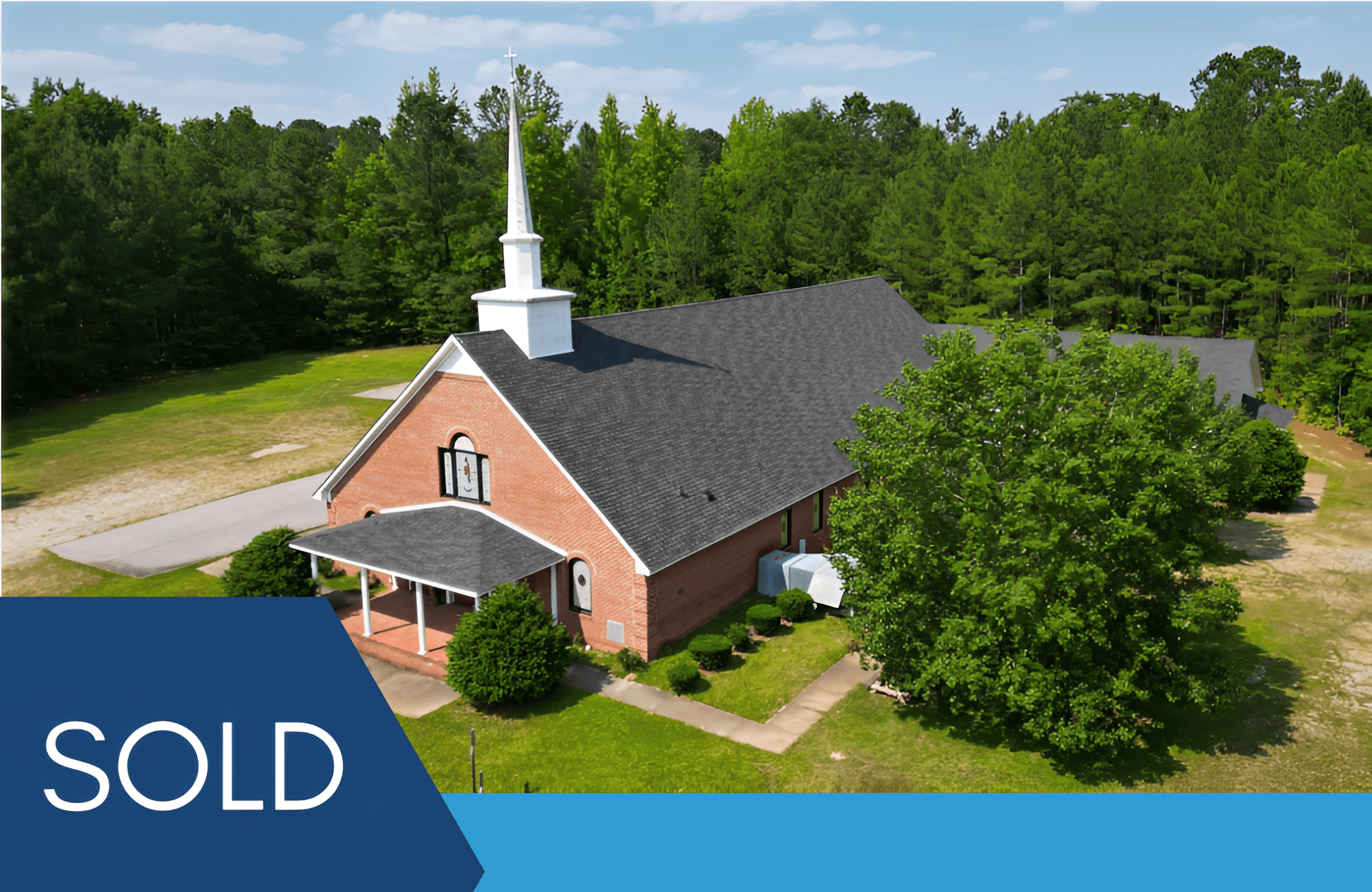 Brick church building with "Sold" sign.