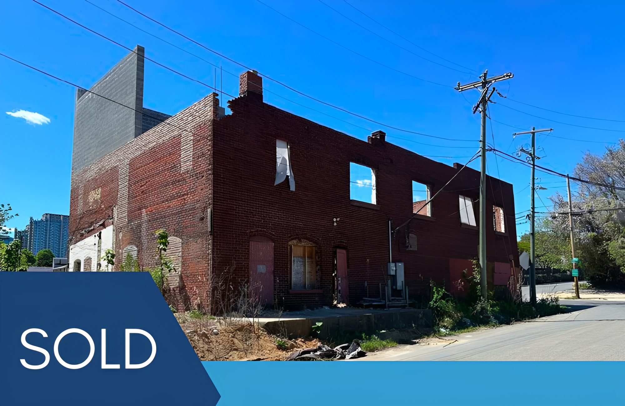 Abandoned brick building marked as sold.